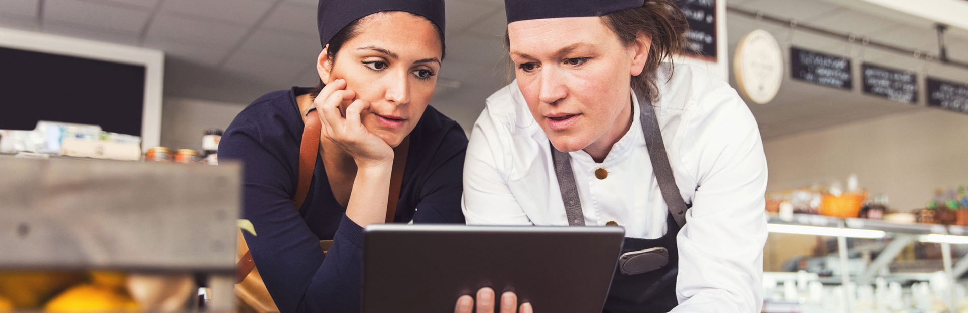two women from a bakery looking through a tablet screen together