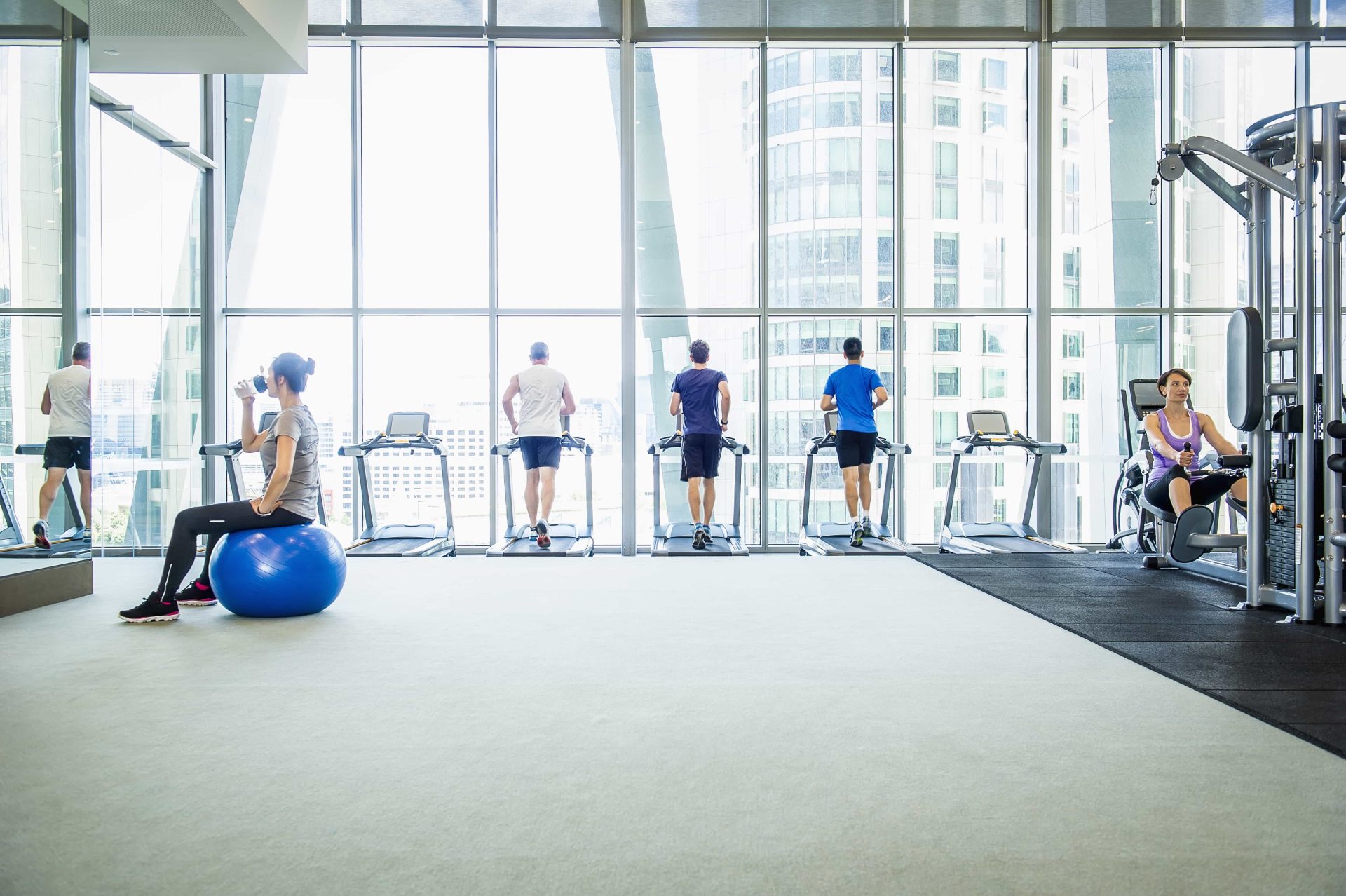 group of various older adults exercising on gym equipment overlooking an array of buildings in downtown