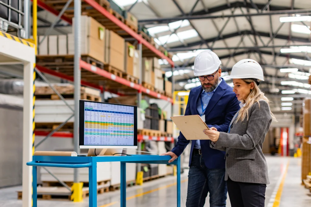 Female engineer and male project manager standing in modern industrial factory